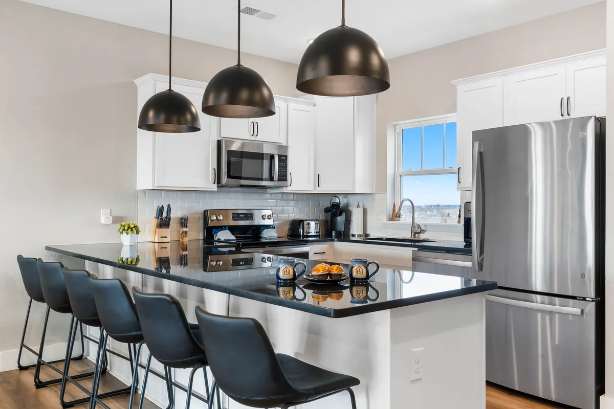 A contemporary chef’s kitchen highlighted by an expansive island with bar stools, upscale appliances, and stylish pendant lights overhead. The layout encourages social interaction, with space for multiple people to cook or gather.