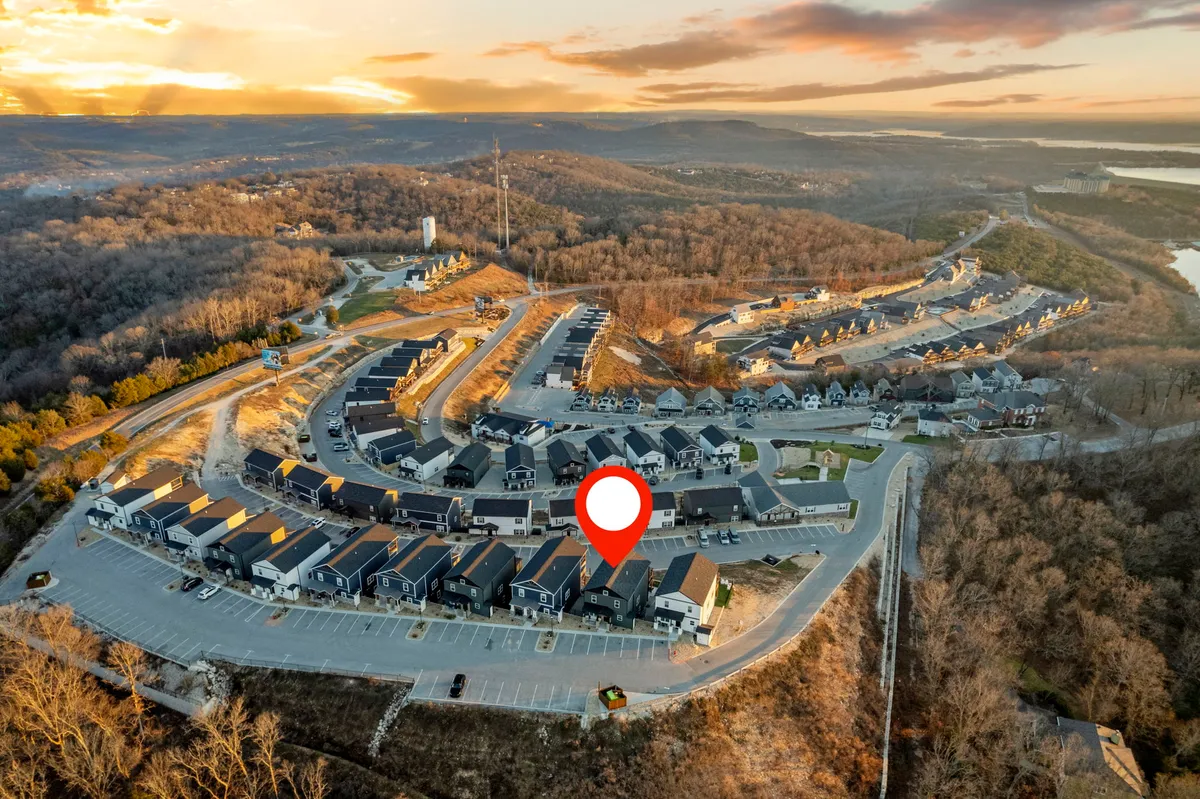 This image presents a calm and inviting exterior view of a row of houses along a curved road, with surrounding hills and a colorful sunset sky. The landscape suggests open spaces and walkable areas, ideal for neighborhood strolls and pet-friendly outdoor adventures.