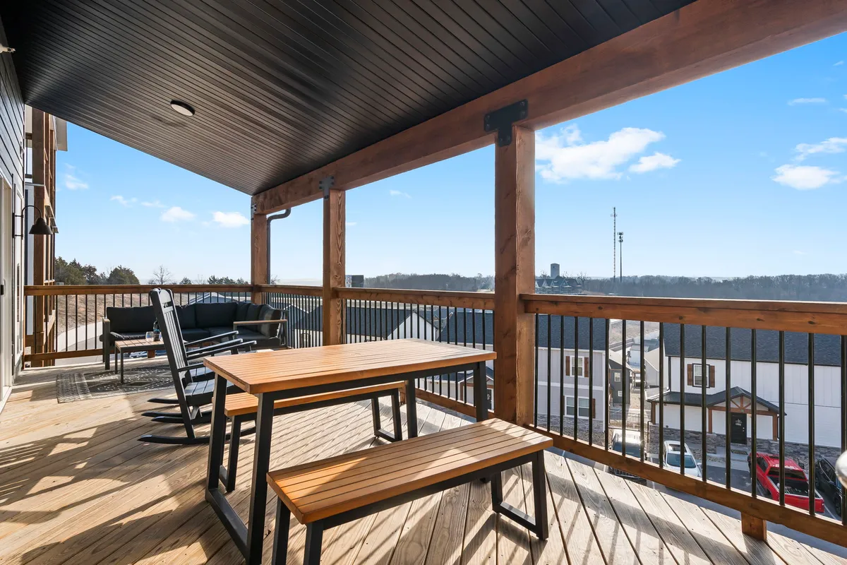A stylish outdoor dining area with a wooden table and black chairs set against a backdrop of rolling landscape. The view from the table extends toward the horizon, with soft sunset lighting adding warmth. This space is ideal for socializing, al fresco meals, or simply enjoying the expansive outdoor scenery.