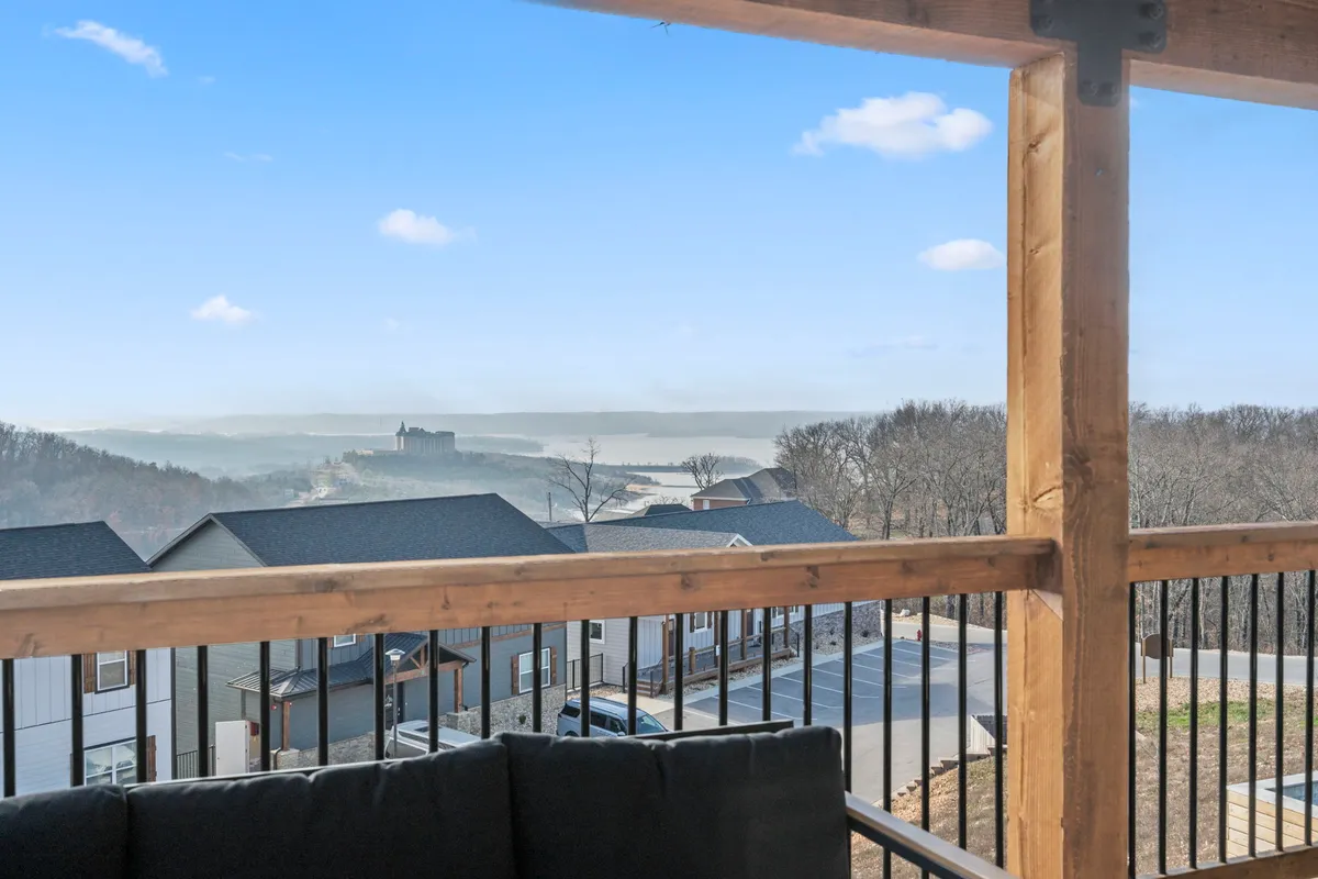 An inviting view from a wooden deck or balcony, looking out over expansive natural landscape. Outdoor seating and a wooden railing encourage guests to relax outdoors with pets, enjoy the view, or host gatherings.