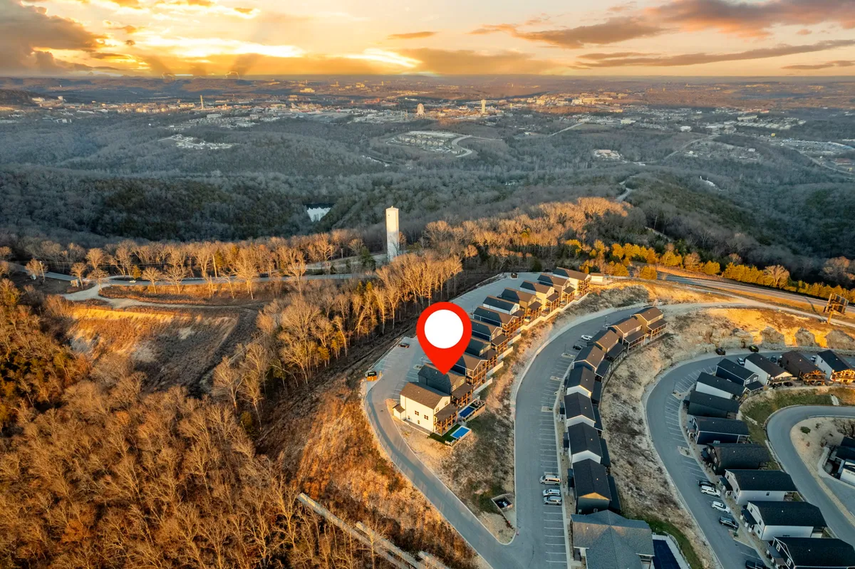 A wide-angle exterior shot of the residential area nestled in gentle hills, with a dramatic sunset sky overhead. The image suggests proximity to nature trails, peaceful evening walks, and a strong connection to the outdoors and the local landscape.