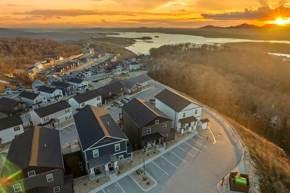 An exterior view capturing a row of houses along the lake at sunset, with mountains in the background and a peaceful ambiance. The scene suggests opportunities for outdoor gatherings, scenic evening moments, and easy access to Branson’s attractions.