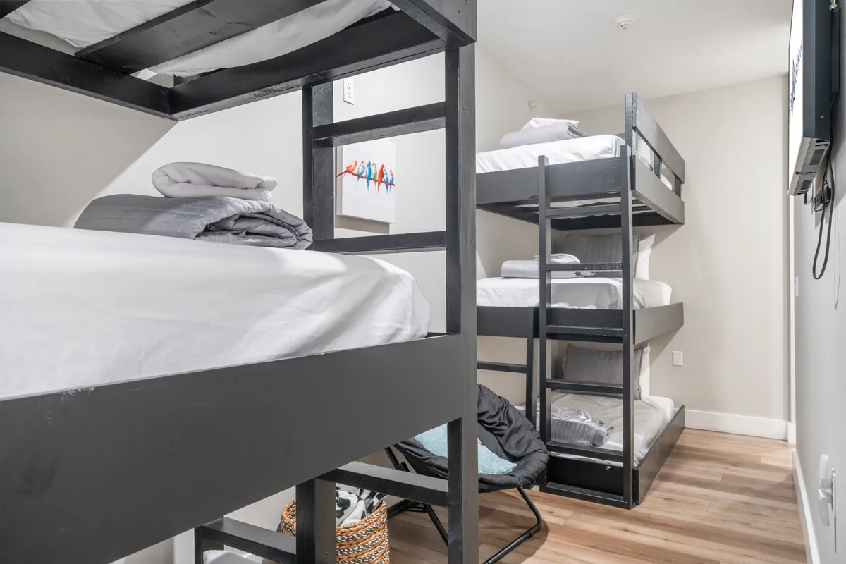 A vibrant bunk room designed for kids or groups of friends, featuring built-in bunk beds, playful artwork, and a cozy chair in the corner. The room is inviting and youthful, perfect for late-night chats or reading.